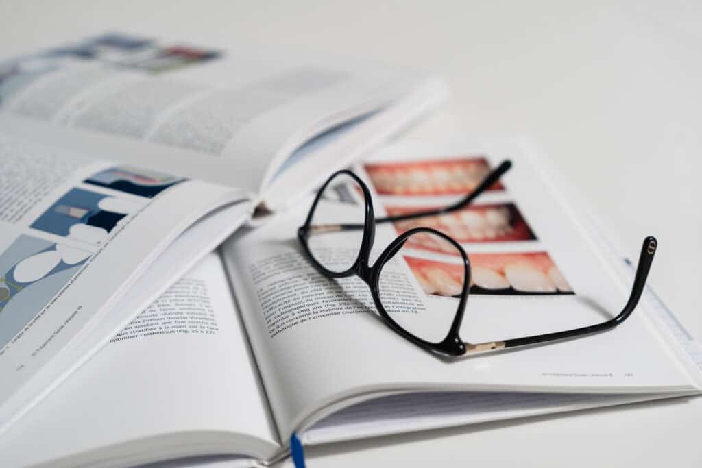 Open magazine with eyeglasses on top, showcasing dental and eye care services at Ardentis Dental Clinic.