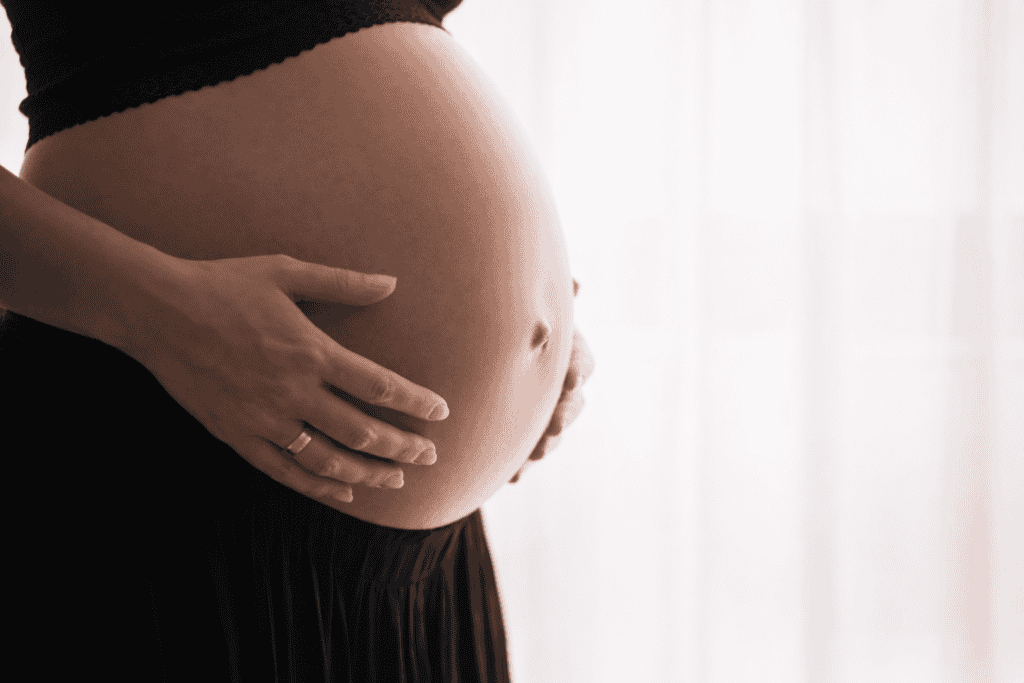 Pregnant woman gently holding her belly, showcasing prenatal care and maternity health.