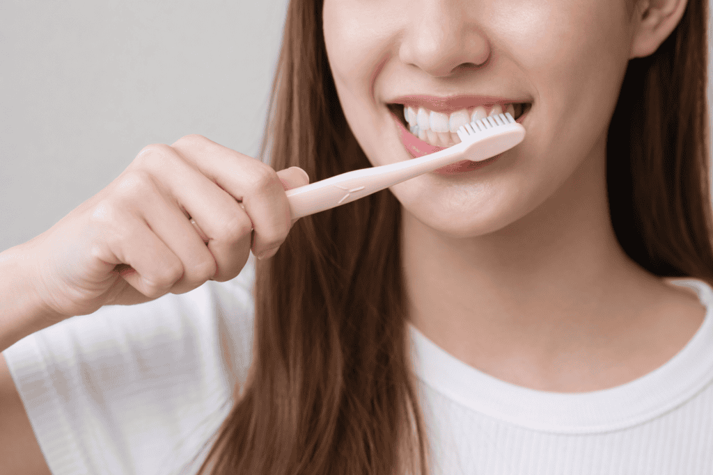 Woman brushing her teeth with a toothbrush, emphasizing dental health and oral hygiene practices.