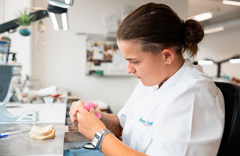 Apprentie technicienne dentaire travaillant sur un modèle en laboratoire