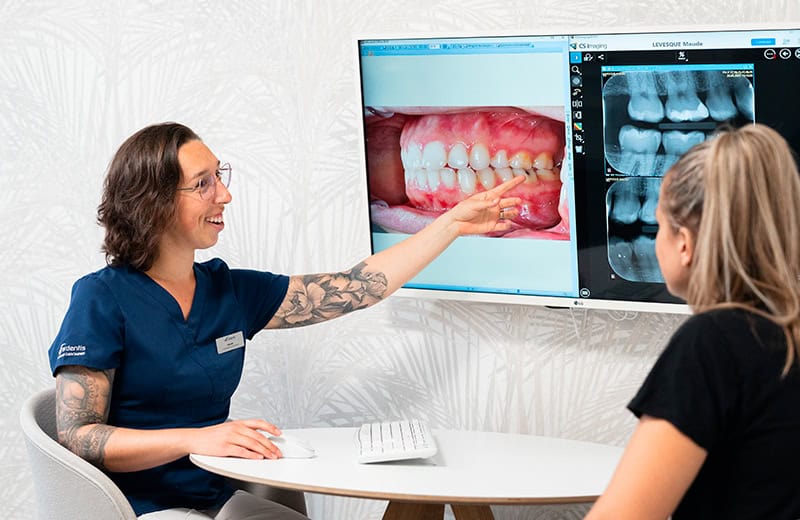 Dentist explaining dental X-ray images and oral health to a patient during a consultation at Ardentis dental clinic.
