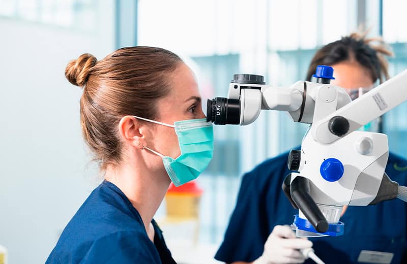 Dental professionals using a microscope for advanced dental research and treatment at Ardentis clinic.