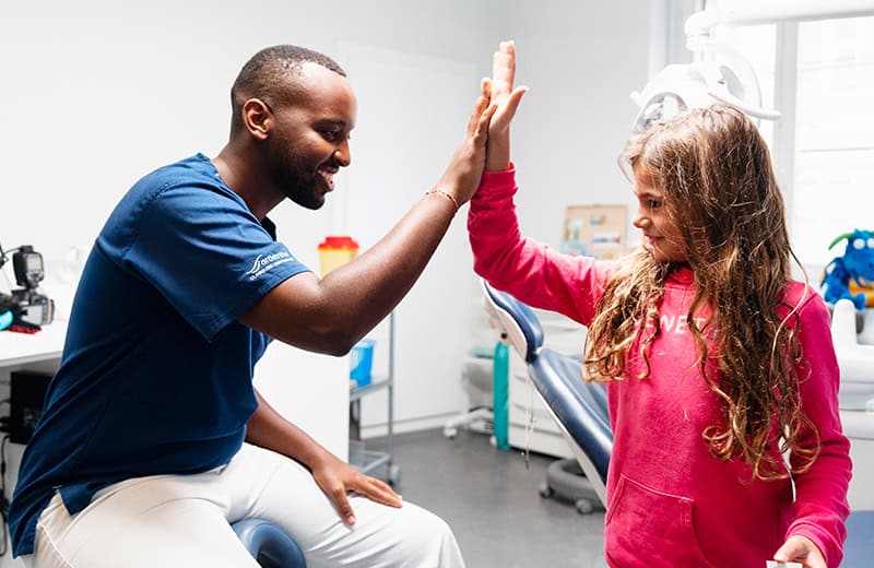 Dentiste pédiatrique faisant un high five avec une enfant après consultation