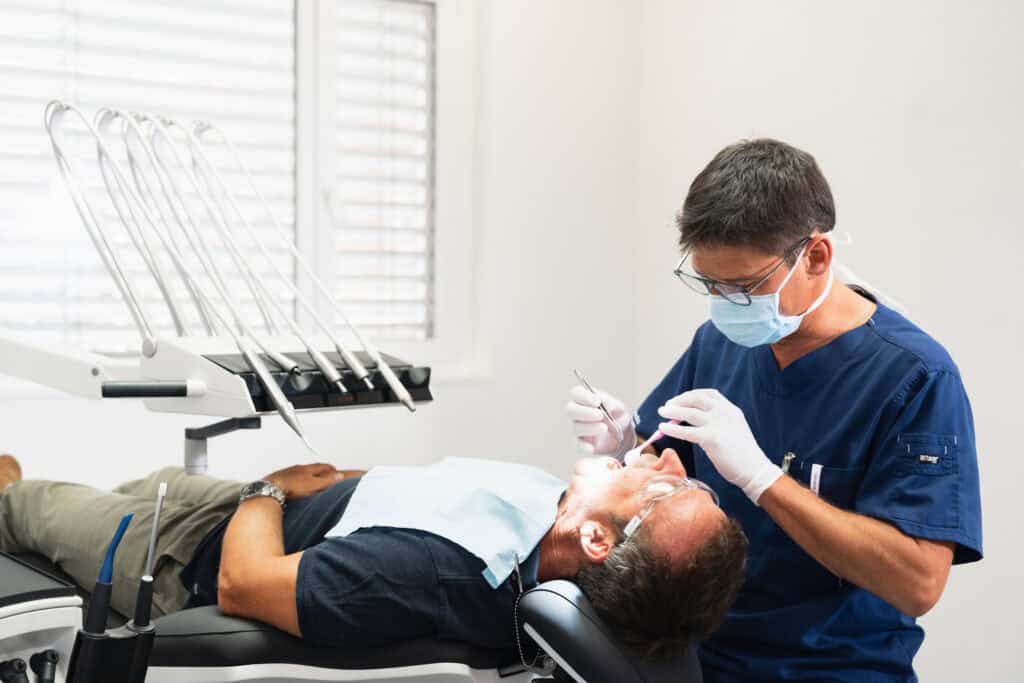 Dentiste effectuant un traitement dentaire sur un patient allongé